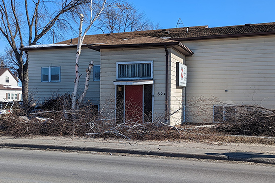 A formally abandoned building at 624 North Washington St. in Grand Forks, ND, with brush and other debris lying out front